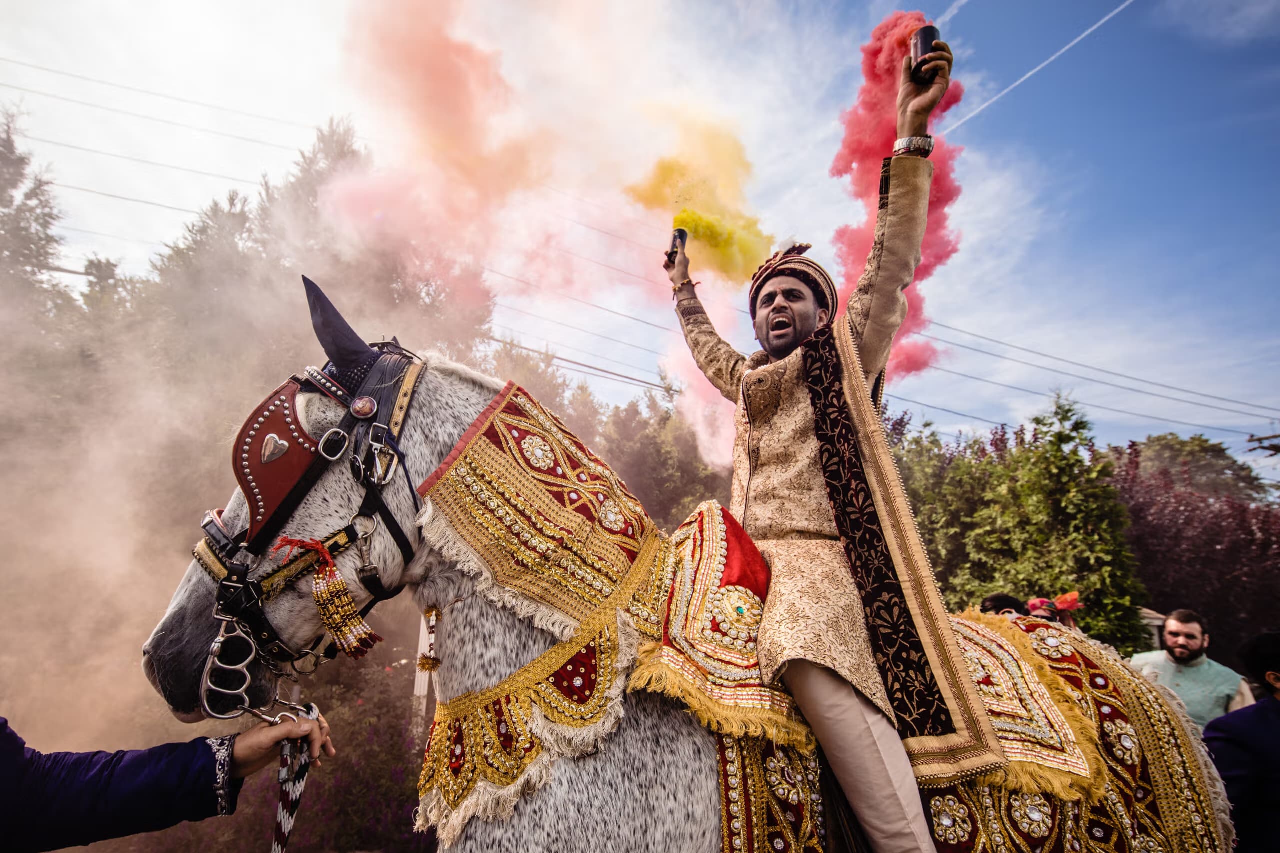 Groom celebrating on horseback amid colourful powder during a Baraat